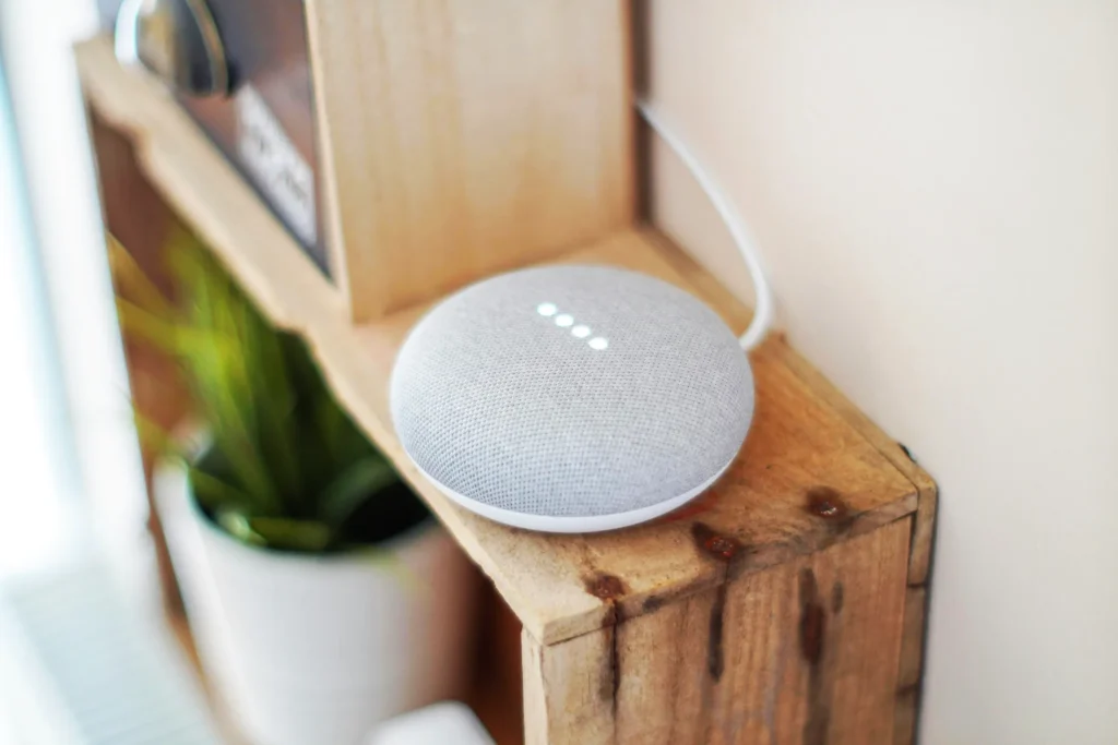 Google Nest smart speaker in light grey on a shelf
